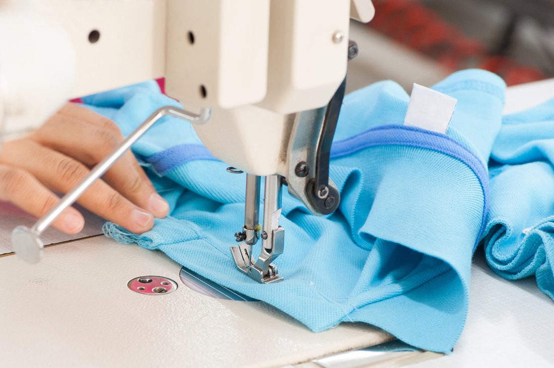 Sewing a blue polo shirt on an industrial machine